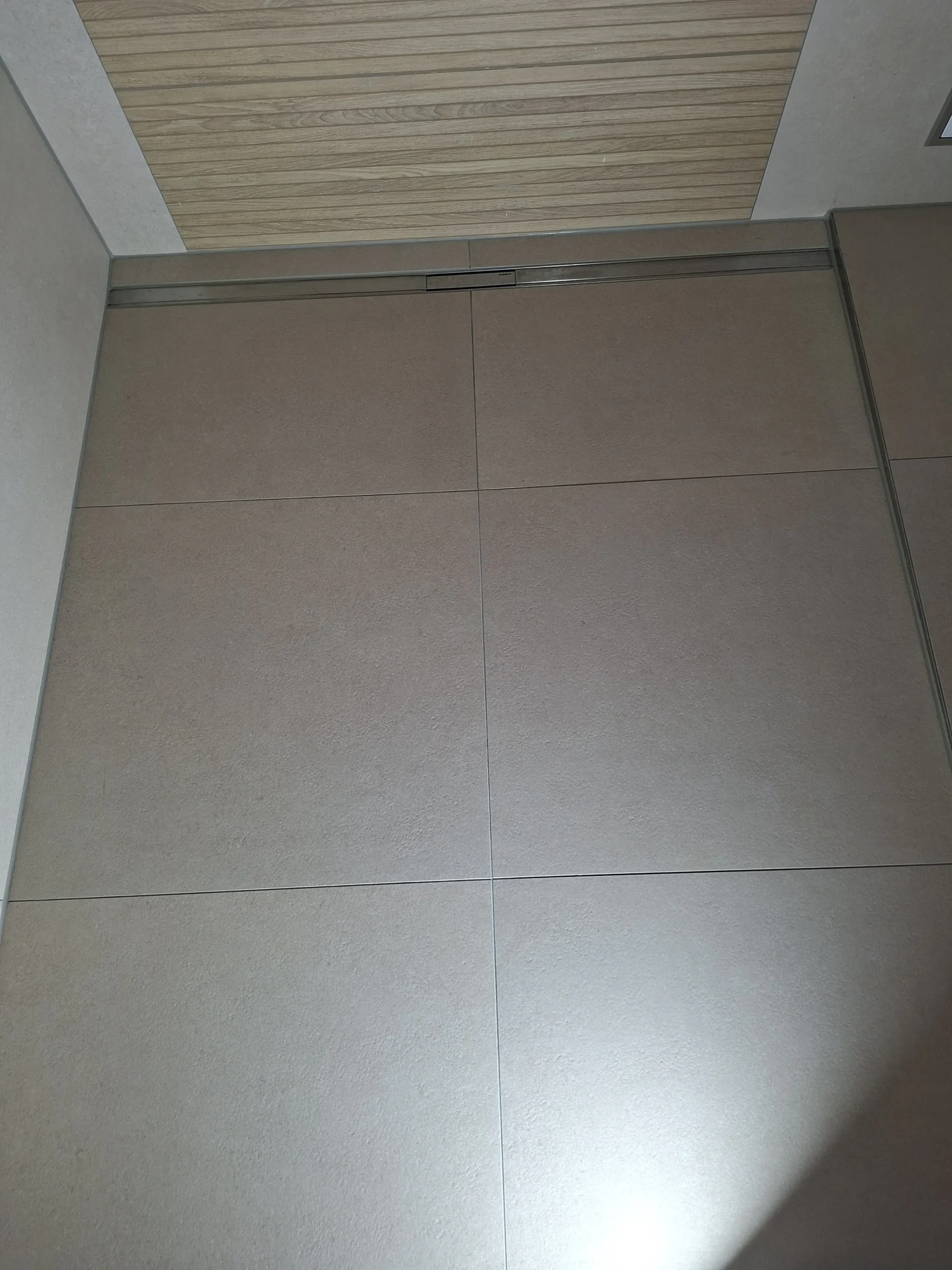 Modernes Badezimmer mit bodenebener Dusche, großformatigen Fliesen und Holzoptik-Akzentwand in Düsseldorf – MK Innenausbau